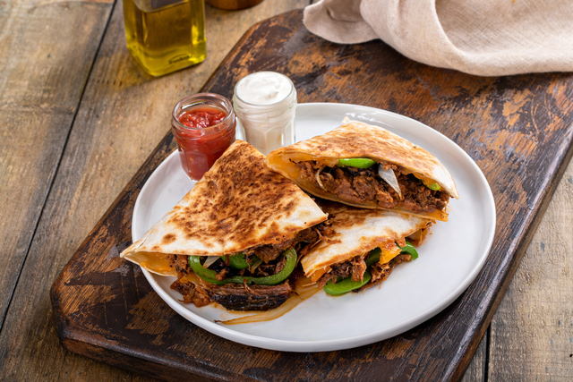 Brisket, peppers and onions quesadillas cut on a plate