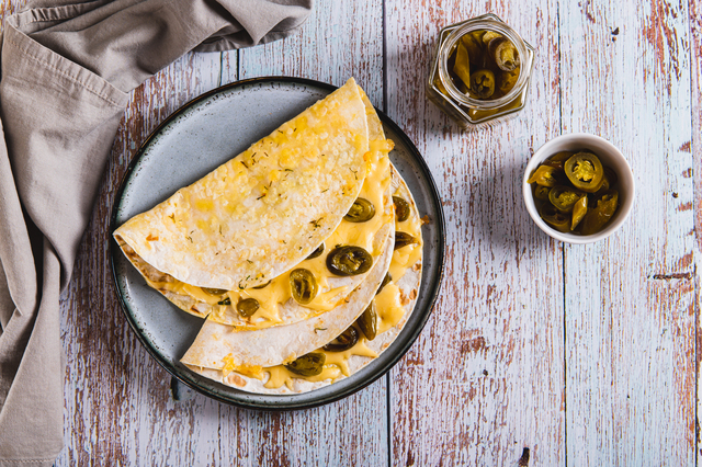 Spicy quesadilla with cheese and jalapeno pepper on a plate on t